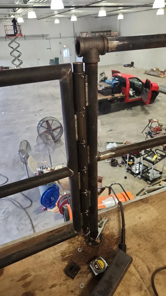 Fresh structural weld on a yellow excavator boom during a heavy equipment repair