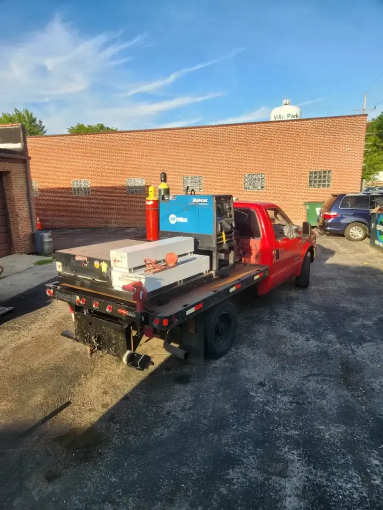 Mobile welder making an on-site repair under a blue sky in Villa Park, IL